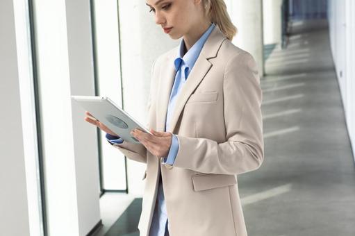 オフィスの通路でタブレットを使う女性 ビジネスウーマン,ビジネス,女性の写真素材