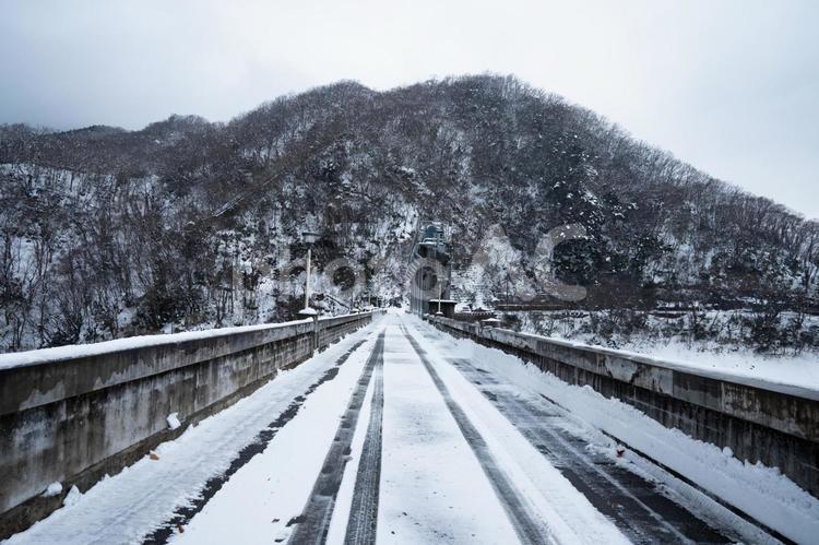 雪の積もった一本道とタイヤの跡 豪雪地帯,吊り橋,冬景色の写真素材