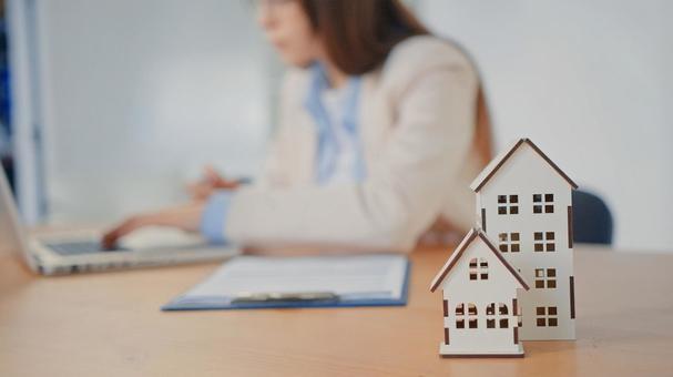 家と模型を置いて仕事をする女性 保険業,事務職,接客業の写真素材