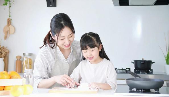 キッチンで楽しそうに料理をする母娘の写真