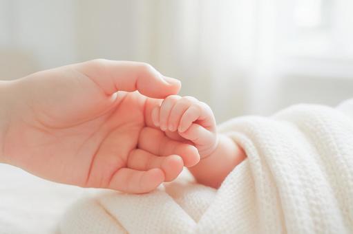 赤ちゃんと手を繋ぐお母さんの写真