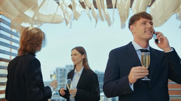 笑顔で通話するグラスを持った男性の写真