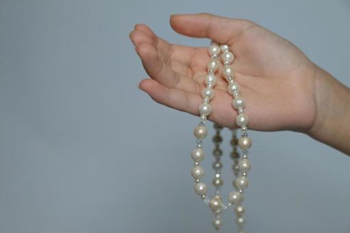 真珠のネックレスを持つ手とコピースペース 真珠,パール,ネックレスの写真素材