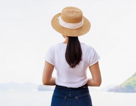 白いTシャツに麦わら帽子を被った女性 白いTシャツに麦わら帽子を被った女性の写真