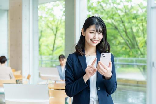 スマホを操作するビジネスウーマン スマホを操作するビジネスウーマン スマホ,笑顔,ビジネスウーマンの写真素材