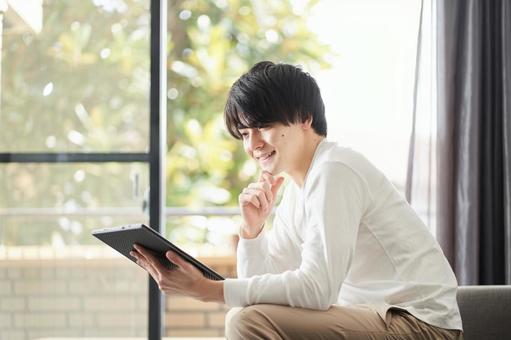 A man using a tablet in his living room, tavoletta, un uomo, vivente, JPG