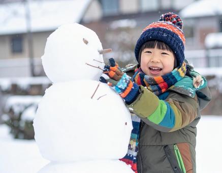雪だるまを作って喜ぶ子供の冬の屋外風景 雪だるまを作って喜ぶ子供の冬の屋外風景の写真