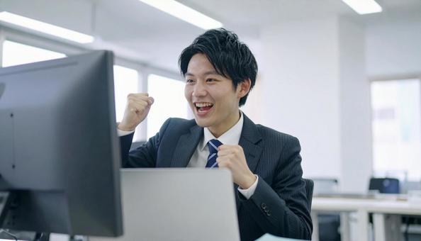 オフィスで喜ぶビジネスマン オフィスで喜ぶビジネスマンの写真