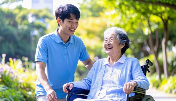 散歩する車椅子の高齢女性と男性介護士 散歩する車椅子の高齢女性と男性介護士の写真