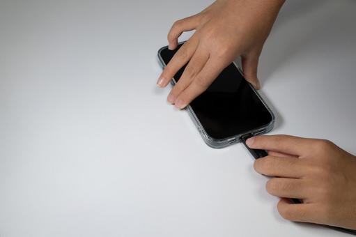 スマートフォンに充電ケーブルを差し込む手 スマートフォン,充電,ケーブルの写真素材