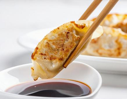 焼き餃子をタレに浸す瞬間のクローズアップ 焼き餃子をタレに浸す瞬間のクローズアップの写真