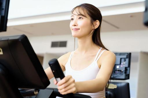 ジムでエアロバイクを漕ぐ女性 フィットネス,トレーニング,エクササイズの写真素材