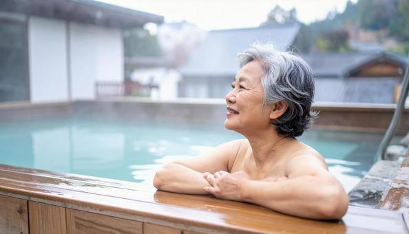 温泉につかってリラックスするシニア女性 温泉につかってリラックスするシニア女性の写真
