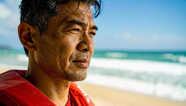 砂浜から海を見つめるライフセーバーの男性 砂浜から海を見つめるライフセーバーの男性の写真