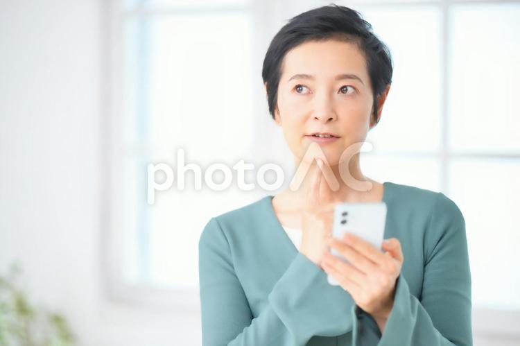 携帯を持ったまま考える女性 女性,主婦,携帯の写真素材