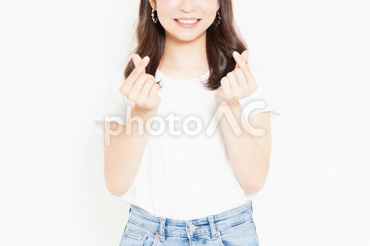 ハートのジェスチャーをするTシャツを着た若い女性 ハート,気持ち,愛の写真素材