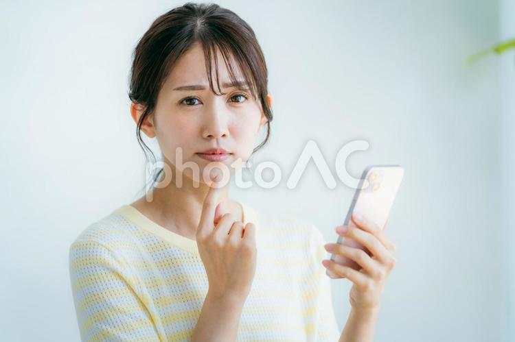 部屋でスマホを操作する女性 スマホ,女性,困るの写真素材