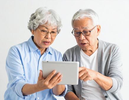 タブレットを見ながら話すシニア夫婦 タブレットを見ながら話すシニア夫婦の写真