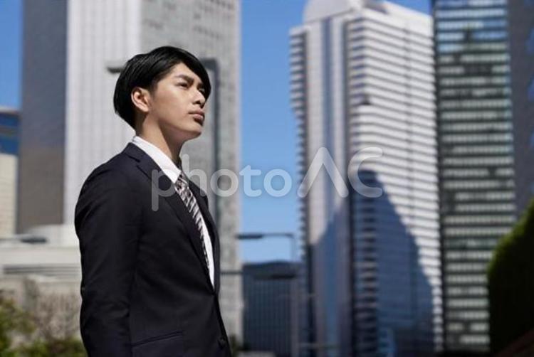 オフィス街で真剣な表情で立つビジネスマン ビジネスマン,男性,真剣の写真素材