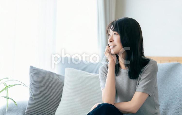 リビングのソファに座る笑顔の女性 女性,ソファ,笑顔の写真素材