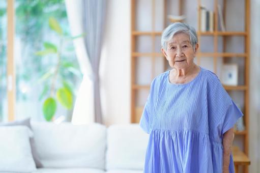 カメラ目線の青いワンピースのおばあちゃん 女性,立つ,穏やかの写真素材