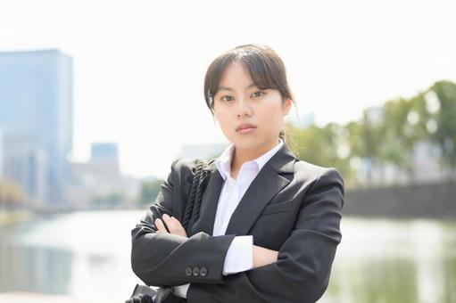 ビル街でカメラ目線のスーツの女性 ビル街でカメラ目線のスーツの女性 日本人,女性,20代の写真素材