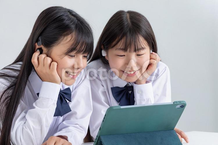 イヤホンをしてタブレットを見る学生 子ども,制服,サインの写真素材