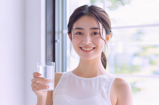 笑顔で水を飲む健康的な女性 笑顔で水を飲む健康的な女性の写真