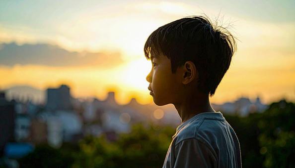 夕焼けの空を見つめる日本人の少年 夕焼けの空を見つめる日本人の少年の写真
