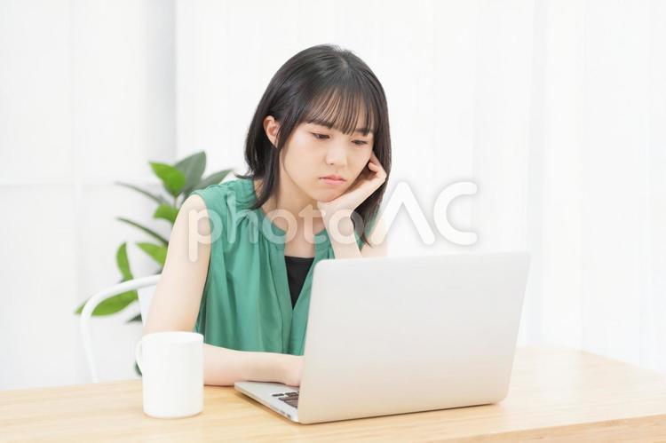 肘をついて考え事をしている若い女性 ノートパソコン,パソコン,女性の写真素材