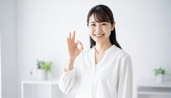 笑顔でOKサインをする白いブラウスの女性 笑顔でOKサインをする白いブラウスの女性の写真