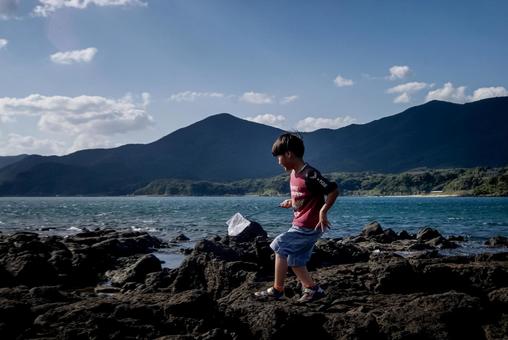 ＜素材＞磯でガサガサ（小魚捕獲）する子供 子供,磯遊び,海の写真素材