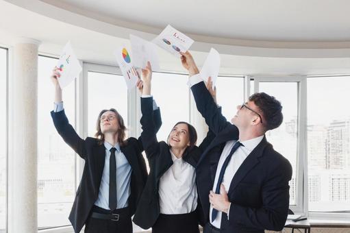 資料を高くあげて持つ男女の写真