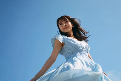 夢見るような表情の日本人女性と青空の写真