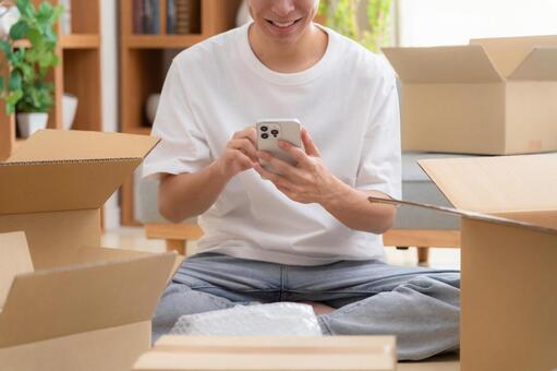 引っ越しでスマホを見る若い男性 引越し,荷造り,男性の写真素材