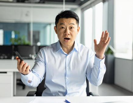 電話をしながら驚く男性社員の写真