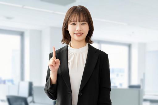 人差し指を立てて案内する笑顔の女性 女性,笑顔,指の写真素材