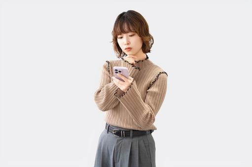 スマホを見て考える女性・ビジネスウーマン スマホを見て考える女性・ビジネスウーマン 女性,困る,考えるの写真素材