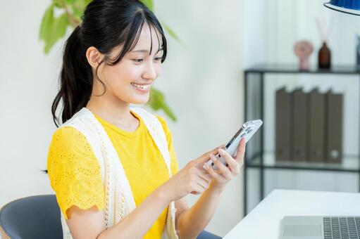 スマホを操作する若い女性 ビジネスウーマン,若い女性,笑顔の写真素材