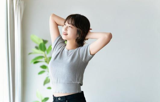 窓際でストレッチをする女性 窓際でストレッチをする女性の写真