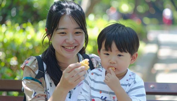 公園でおやつを食べる親子の写真