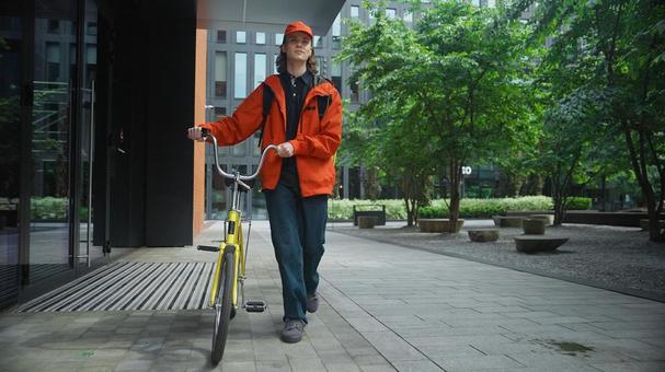 自転車を押して歩いている配達バッグを背負った男性 配達,フードデリバリー,デリバリーの写真素材