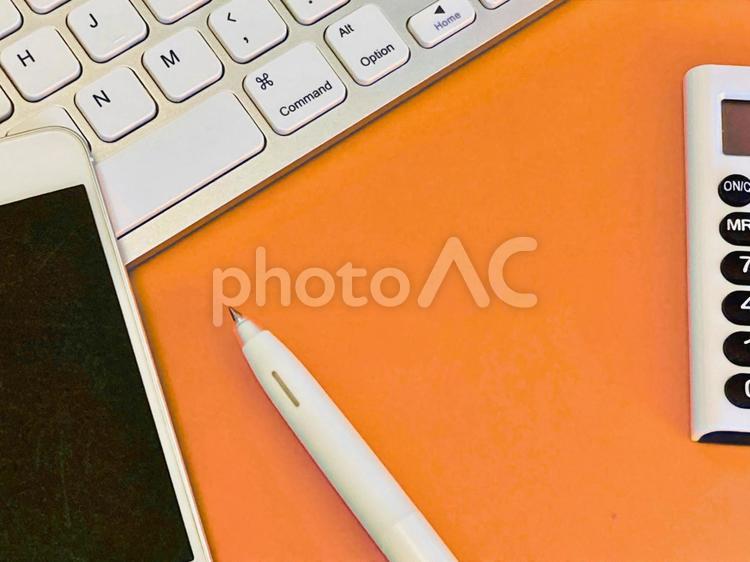 スマホとキーボードと電卓（オレンジ背景） 仕事,ビジネス,ビジネスツールの写真素材