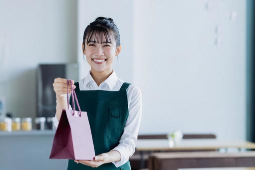 商品を渡す若い女性の店員 商品を渡す若い女性の店員の写真