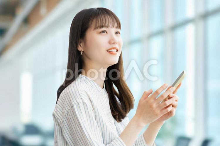 スマホを使う笑顔の女性・ビジネスウーマン 女性,スマホ,笑顔の写真素材