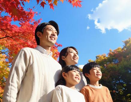 青空の下で秋の紅葉を仲良く鑑賞する家族 青空の下で秋の紅葉を仲良く鑑賞する家族の写真