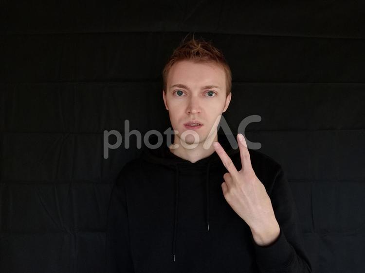 2をジェスチャーで表している外国人男性　黒バック 二,2,にの写真素材