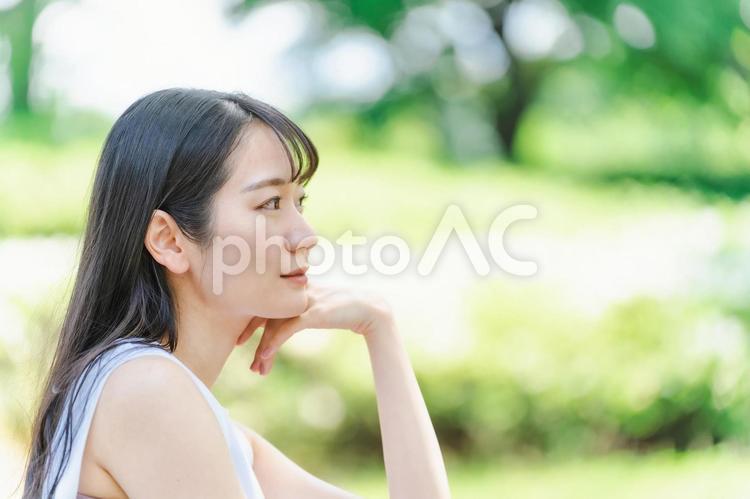 新緑の中で頬杖をつく日本人女性（悩む） 女性,横顔,考えるの写真素材