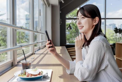 カフェでスマホを使う女性 カフェでスマホを使う女性の写真