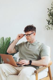 椅子に座って膝の上でノートパソコンを使っている男性 男性,外国人,欧米人の写真素材